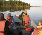 Photo of four students in a boat on a lake, looking out at their study site
