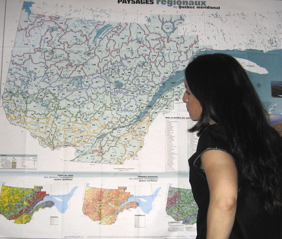 Photo of Édith Bégin looking at a geographical map of Quebec 